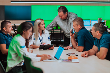 Image showing Group of security guards sitting and having briefing In the system control room They're working in security data center surrounded by multiple Screens