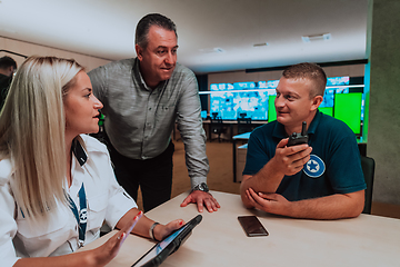 Image showing Group of security guards sitting and having briefing In the system control room They're working in security data center surrounded by multiple Screens