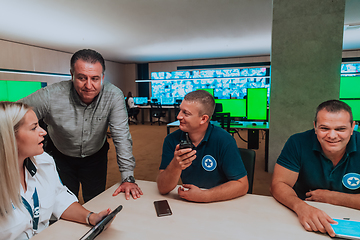 Image showing Group of security guards sitting and having briefing In the system control room They're working in security data center surrounded by multiple Screens