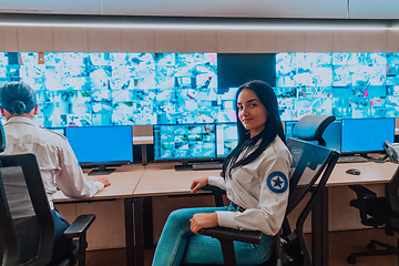 Image showing Female security operator working in a data system control room offices Technical Operator Working at workstation with multiple displays, security guard working on multiple monitors