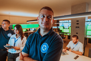 Image showing Group of security operators working in a data system control room Technical Operators Working at workstation with multiple displays, security guards working on multiple monitors in surveillan