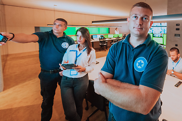 Image showing Group of security operators working in a data system control room Technical Operators Working at workstation with multiple displays, security guards working on multiple monitors in surveillan