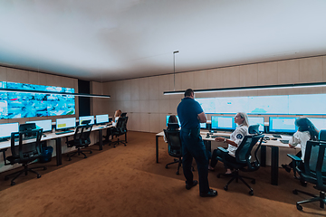 Image showing Group of security operators working in a data system control room Technical Operators Working at workstation with multiple displays, security guards working on multiple monitors in surveillan