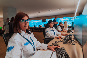 Image showing Group of Security data center operators working in a CCTV monitoring room looking on multiple monitors.Officers Monitoring Multiple Screens for Suspicious Activities