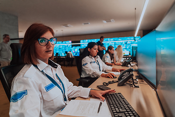 Image showing Group of Security data center operators working in a CCTV monitoring room looking on multiple monitors.Officers Monitoring Multiple Screens for Suspicious Activities