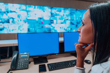 Image showing Female security operator working in a data system control room offices Technical Operator Working at workstation with multiple displays, security guard working on multiple monitors