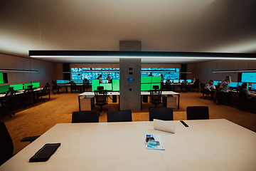 Image showing Group of Security data center operators working in a CCTV monitoring room looking on multiple monitors.Officers Monitoring Multiple Screens for Suspicious Activities