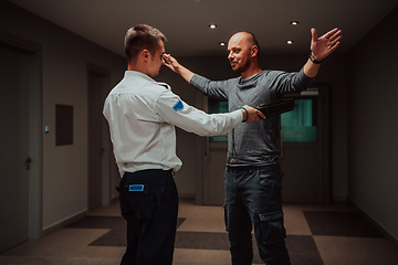 Image showing Security guard making body searching procedure on man for finding hidden objects before entering in treasury department