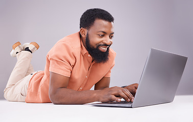 Image showing Happy black man, laptop and studio floor to search social media, online shopping or subscription download. Smile, male model and computer technology for internet, typing email or elearning on website