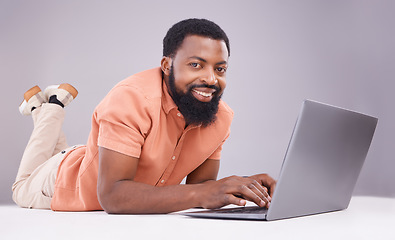 Image showing Portrait, black man and laptop on studio floor to search social media, online shopping or subscription download. Happy male model typing on computer technology, internet blogging or elearning website