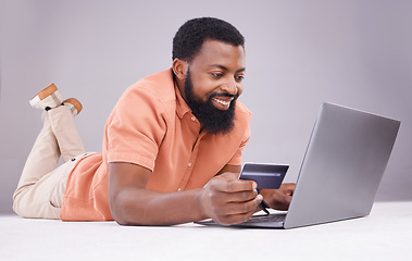 Image showing Credit card, black man and smile on laptop in studio for online shopping, digital payment or money investment. Male model, ecommerce and computer sales for finance, fintech budget or internet banking