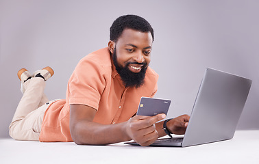 Image showing Happy black man, credit card and laptop in studio for online shopping, digital financial payment and customer money. Male model, ecommerce and computer sales for finance, fintech and banking economy