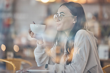 Image showing Thinking, smile and a woman drinking coffee in a cafe to relax alone over the weekend behind glass. Idea, happy and caffeine with an attractive young female enjoying a beverage in a restaurant