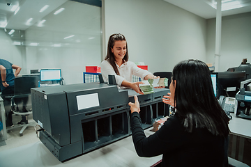 Image showing Bank employees using money counting machine while sorting and counting paper banknotes inside bank vault. Large amounts of money in the bank