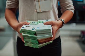 Image showing Bank employees using money counting machine while sorting and counting paper banknotes inside bank vault. Large amounts of money in the bank