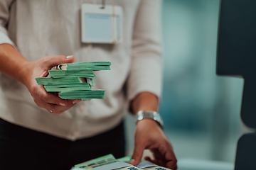 Image showing Bank employees using money counting machine while sorting and counting paper banknotes inside bank vault. Large amounts of money in the bank