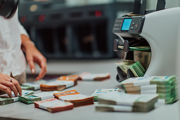 Image showing Bank employees using money counting machine while sorting and counting paper banknotes inside bank vault. Large amounts of money in the bank