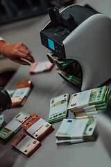 Image showing Bank employees using money counting machine while sorting and counting paper banknotes inside bank vault. Large amounts of money in the bank