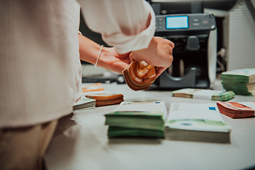 Image showing Bank employees using money counting machine while sorting and counting paper banknotes inside bank vault. Large amounts of money in the bank