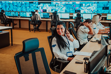 Image showing Group of Security data center operators working in a CCTV monitoring room looking on multiple monitors.Officers Monitoring Multiple Screens for Suspicious Activities