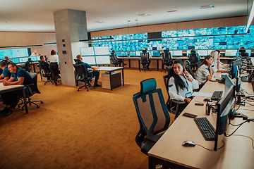 Image showing Group of Security data center operators working in a CCTV monitoring room looking on multiple monitors.Officers Monitoring Multiple Screens for Suspicious Activities