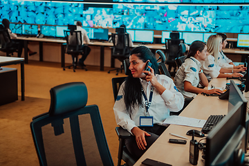 Image showing Group of Security data center operators working in a CCTV monitoring room looking on multiple monitors.Officers Monitoring Multiple Screens for Suspicious Activities