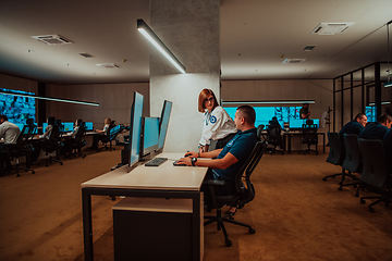 Image showing Group of Security data center operators working in a CCTV monitoring room looking on multiple monitors Officers Monitoring Multiple Screens for Suspicious Activities Team working on the System Contr