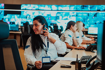 Image showing Group of Security data center operators working in a CCTV monitoring room looking on multiple monitors.Officers Monitoring Multiple Screens for Suspicious Activities