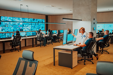 Image showing Group of Security data center operators working in a CCTV monitoring room looking on multiple monitors Officers Monitoring Multiple Screens for Suspicious Activities Team working on the System Contr