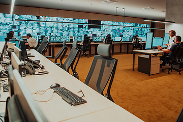 Image showing Group of Security data center operators working in a CCTV monitoring room looking on multiple monitors.Officers Monitoring Multiple Screens for Suspicious Activities