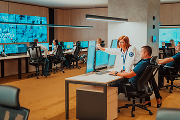 Image showing Group of Security data center operators working in a CCTV monitoring room looking on multiple monitors Officers Monitoring Multiple Screens for Suspicious Activities Team working on the System Contr