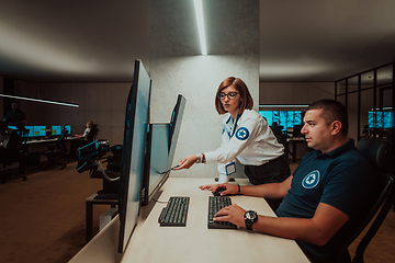 Image showing Group of Security data center operators working in a CCTV monitoring room looking on multiple monitors Officers Monitoring Multiple Screens for Suspicious Activities Team working on the System Contr