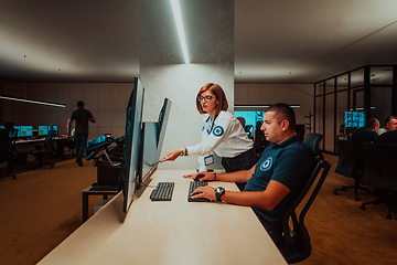 Image showing Group of Security data center operators working in a CCTV monitoring room looking on multiple monitors Officers Monitoring Multiple Screens for Suspicious Activities Team working on the System Contr