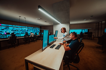 Image showing Group of Security data center operators working in a CCTV monitoring room looking on multiple monitors Officers Monitoring Multiple Screens for Suspicious Activities Team working on the System Contr