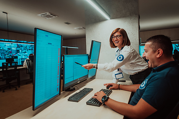 Image showing Group of Security data center operators working in a CCTV monitoring room looking on multiple monitors Officers Monitoring Multiple Screens for Suspicious Activities Team working on the System Contr