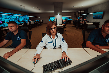 Image showing Group of Security data center operators working in a CCTV monitoring room looking on multiple monitors.Officers Monitoring Multiple Screens for Suspicious Activities