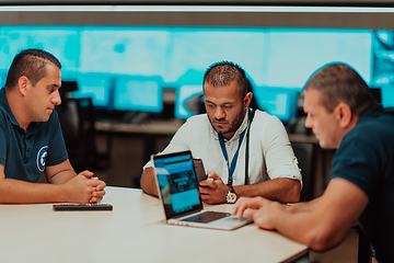 Image showing Group of security guards sitting and having briefing In the system control room They're working in security data center surrounded by multiple Screens