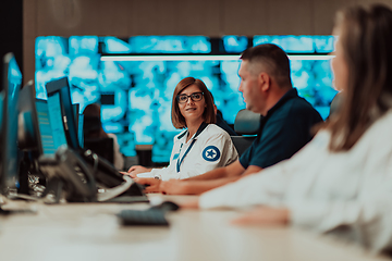 Image showing Group of Security data center operators working in a CCTV monitoring room looking on multiple monitors.Officers Monitoring Multiple Screens for Suspicious Activities