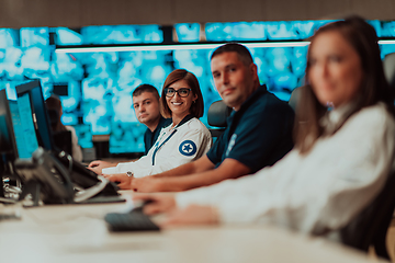 Image showing Group of Security data center operators working in a CCTV monitoring room looking on multiple monitors.Officers Monitoring Multiple Screens for Suspicious Activities