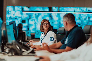 Image showing Group of Security data center operators working in a CCTV monitoring room looking on multiple monitors.Officers Monitoring Multiple Screens for Suspicious Activities