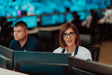 Image showing Group of Security data center operators working in a CCTV monitoring room looking on multiple monitors.Officers Monitoring Multiple Screens for Suspicious Activities