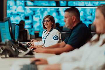 Image showing Group of Security data center operators working in a CCTV monitoring room looking on multiple monitors.Officers Monitoring Multiple Screens for Suspicious Activities