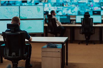 Image showing Group of Security data center operators working in a CCTV monitoring room looking on multiple monitors.Officers Monitoring Multiple Screens for Suspicious Activities