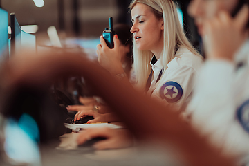 Image showing Group of Security data center operators working in a CCTV monitoring room looking on multiple monitors.Officers Monitoring Multiple Screens for Suspicious Activities