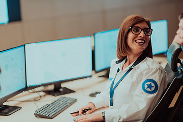 Image showing Female security operator working in a data system control room offices Technical Operator Working at workstation with multiple displays, security guard working on multiple monitors