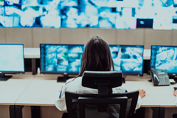 Image showing Female security operator working in a data system control room offices Technical Operator Working at workstation with multiple displays, security guard working on multiple monitors