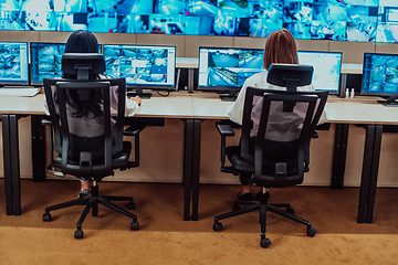 Image showing Group of Security data center operators working in a CCTV monitoring room looking on multiple monitors.Officers Monitoring Multiple Screens for Suspicious Activities