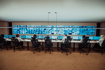 Image showing Group of Security data center operators working in a CCTV monitoring room looking on multiple monitors.Officers Monitoring Multiple Screens for Suspicious Activities