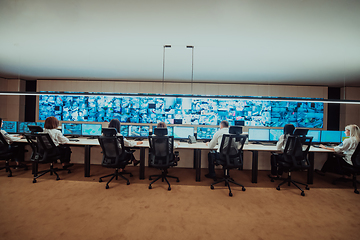 Image showing Group of Security data center operators working in a CCTV monitoring room looking on multiple monitors.Officers Monitoring Multiple Screens for Suspicious Activities