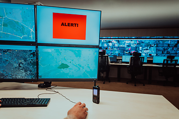 Image showing Group of Security data center operators working in a CCTV monitoring room looking on multiple monitors.Officers Monitoring Multiple Screens for Suspicious Activities